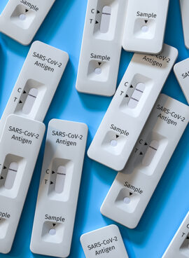 Mass testing for Covid-19 / SARS-CoV-2 infection concept: Several rapid antigen test kits. One kit in the middle showing a positive result (two lines visible)