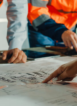 Closeup of team of industrial engineers meeting analyze machinery blueprints consult project on table in manufacturing factory. Working in manufacturing plant or production plant.