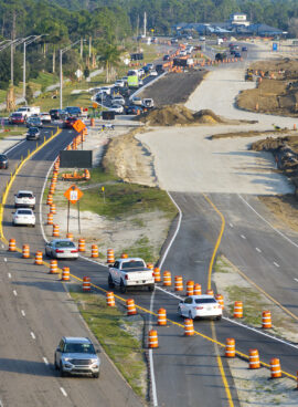 Driving traffic cars on road under construction. Building traffic infrastructure on American roadway with moving cars